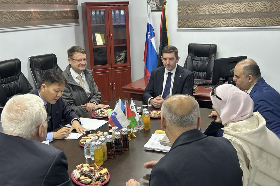 Dr. Musar sedi za mizo z več osebami.