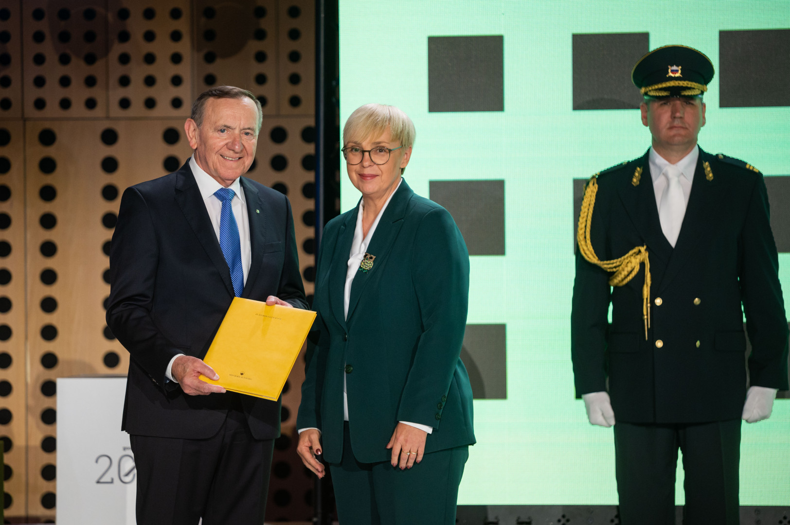 Predsednica in odlikovanec stojita na odru.