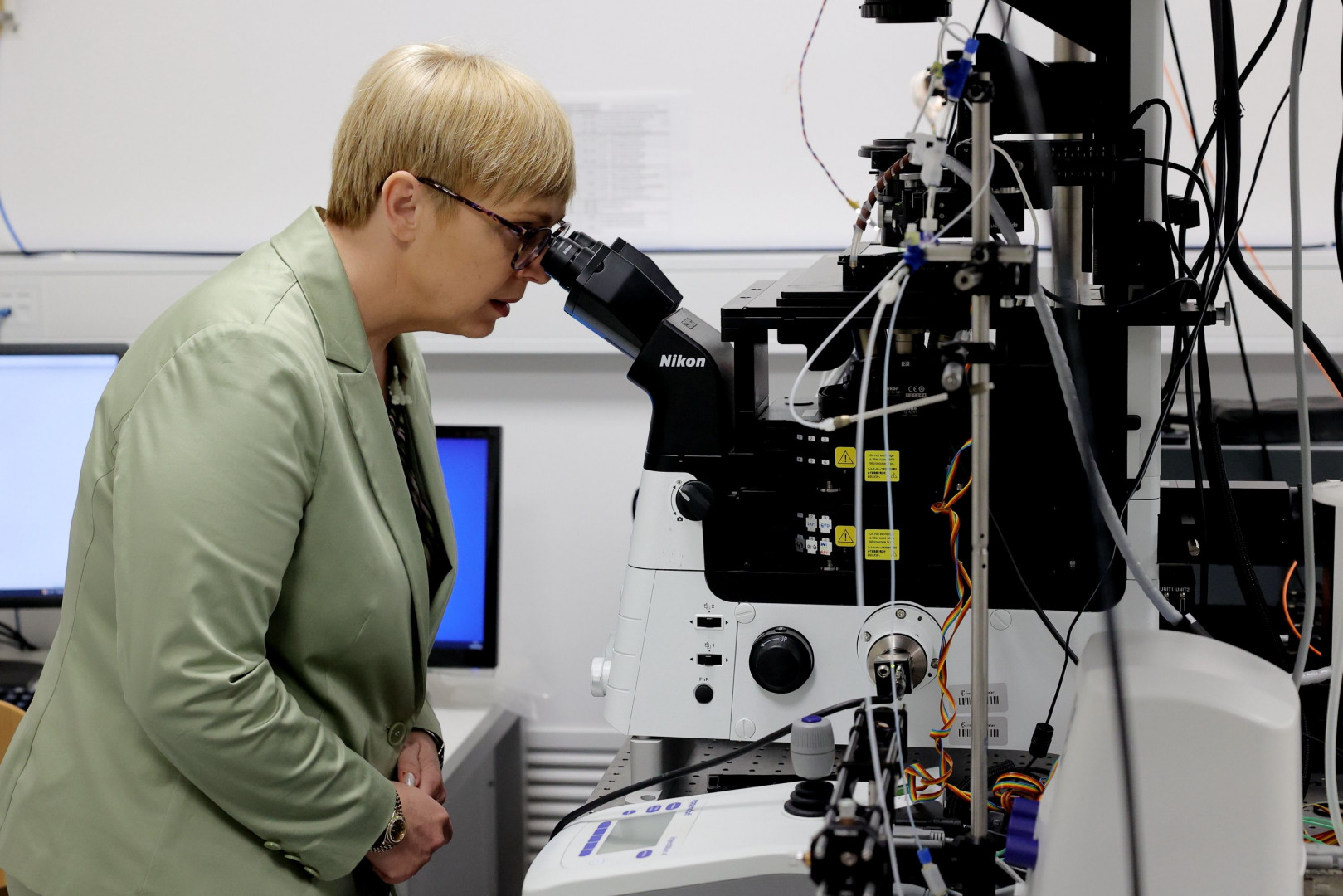 Predsednica gleda v mikroskop.