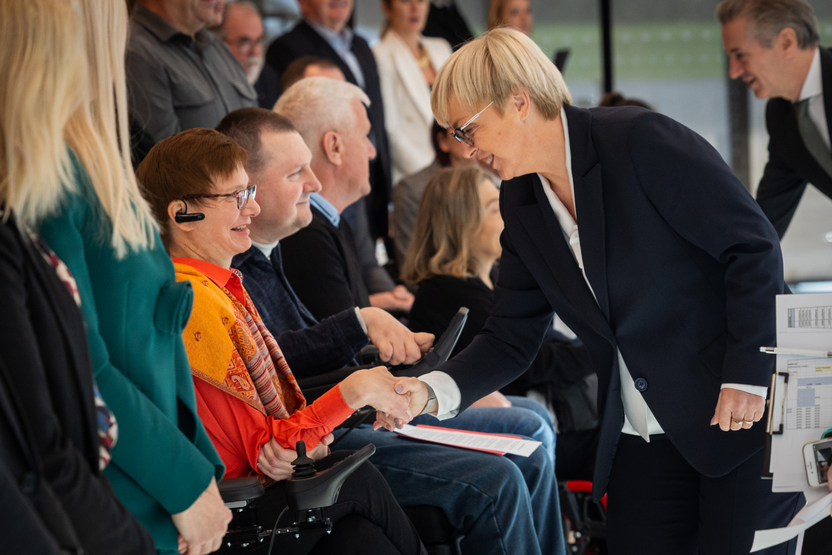 Predsednica se rokuje z udeleženci prireditve.