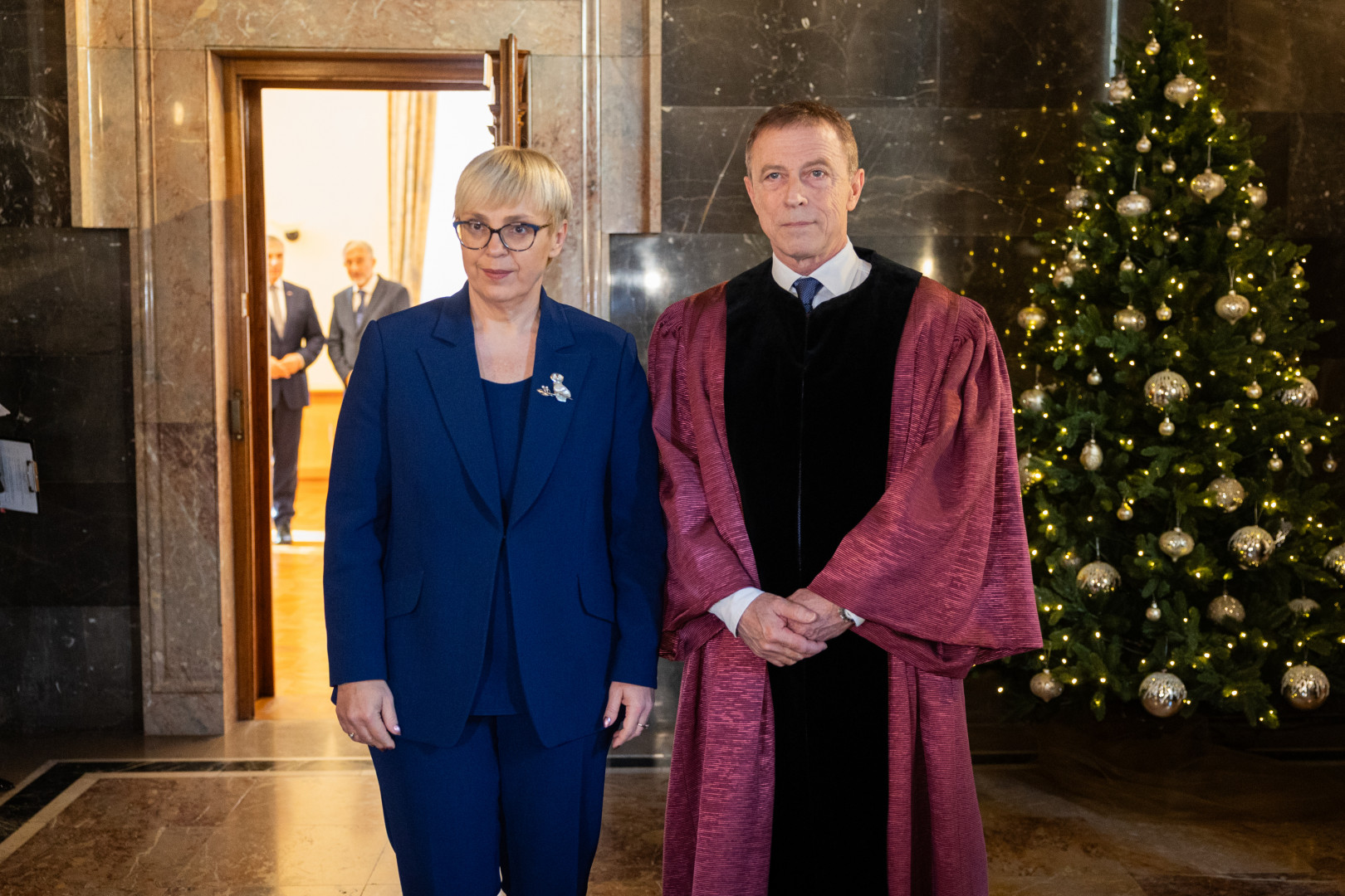 Predsednica in predsednik Ustavnega sodišča stojita na hodniku, v ozadju je novoletna smrečica.