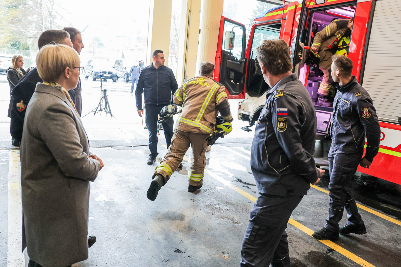 Predsednica opazuje gasilca v uniformi, ki hiti na intervencijo.