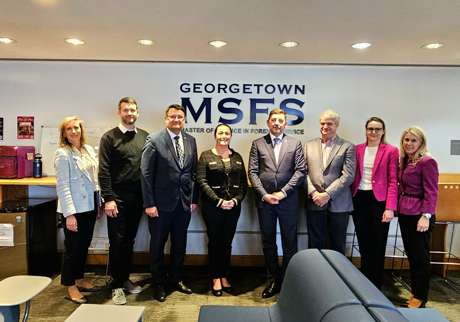 Večja skupina ljudi stoji v notranjem prostoru pred napisom Georgetown MSFS.