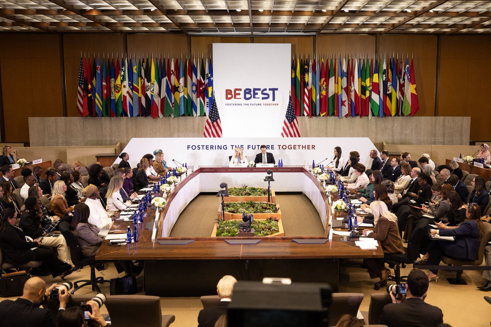 Omizje za katerim sedijo prve soproge in soprogi. Ob steni so zastave.