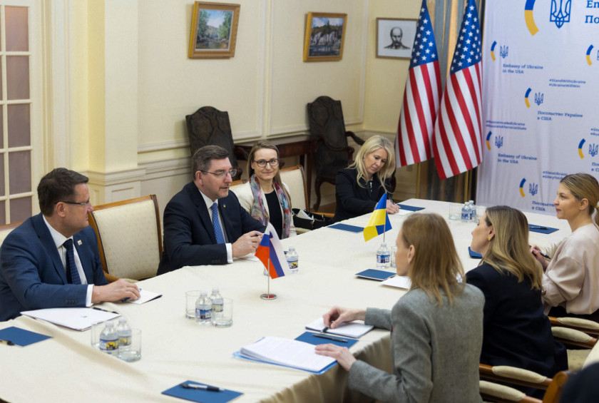 Uradno srečanje delegacij za mizo z ameriško in ukrajinsko zastavo.