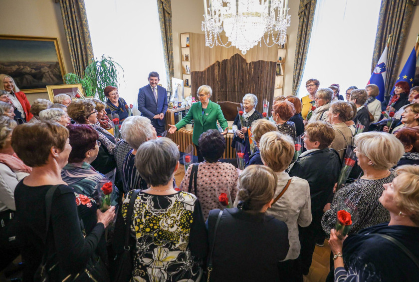 Ženske v predsedničini pisarni okrog predsednice, ki govori.