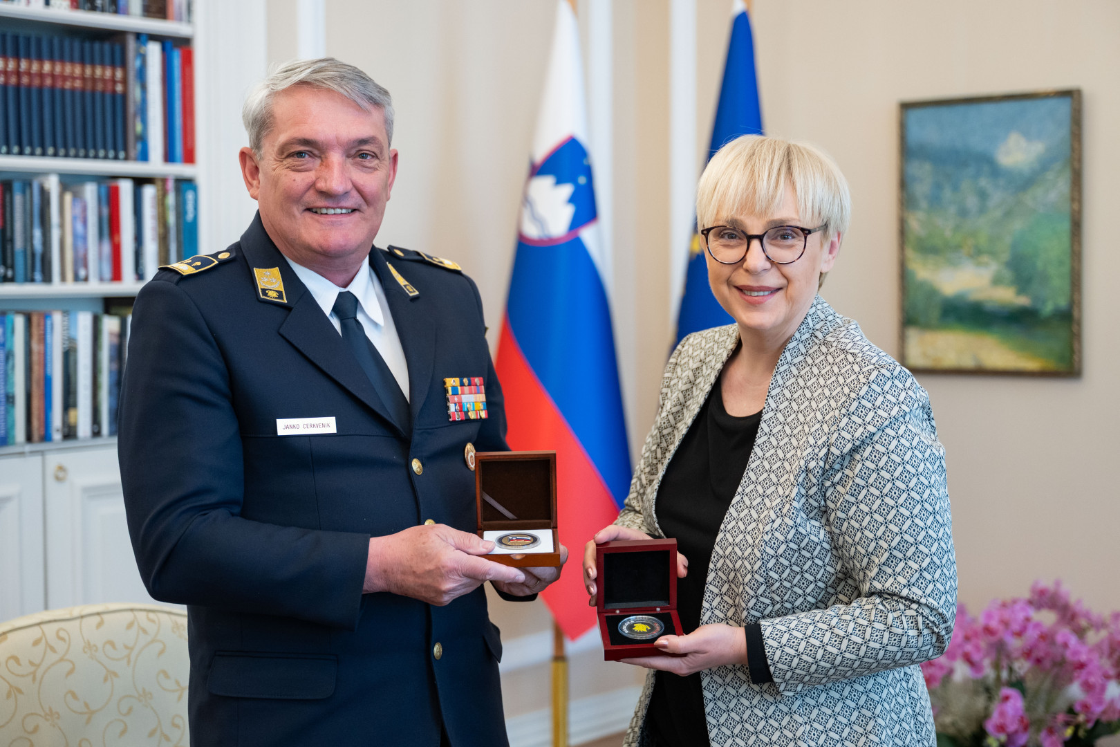 Predsednica in poveljnik gasilske zveze proti fotoaparatu kažeta vsaj svoj spomninski kovanec.