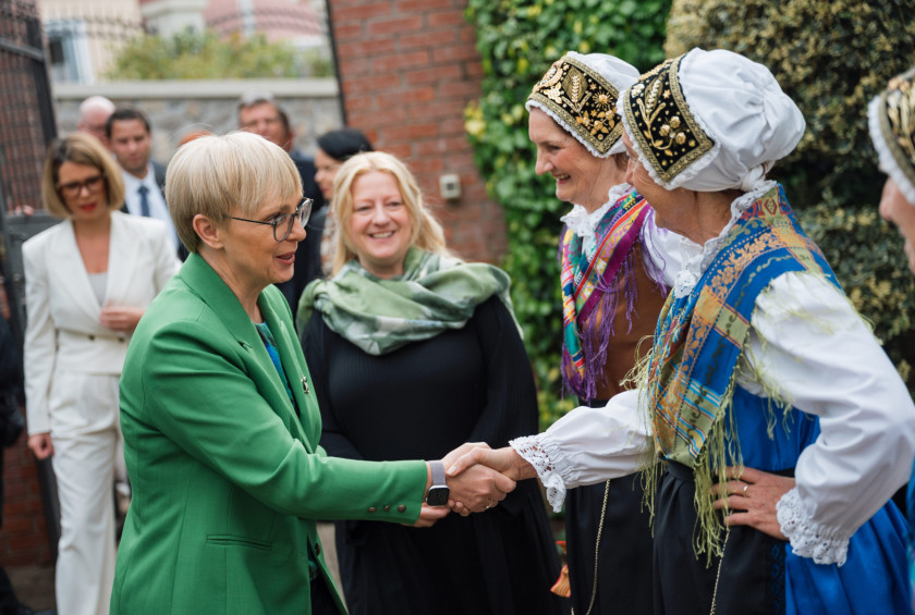 Predsednica se ob prihodu rokuje z dvema osebama v slovenskih narodnih nošah.