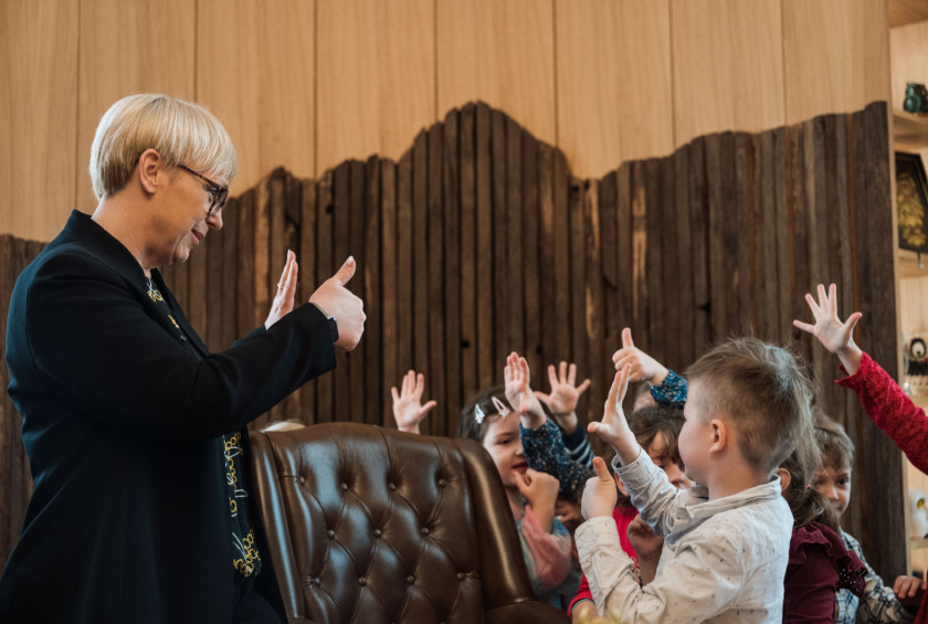 Predsednica in otroci s prsti kažejo različna števila.