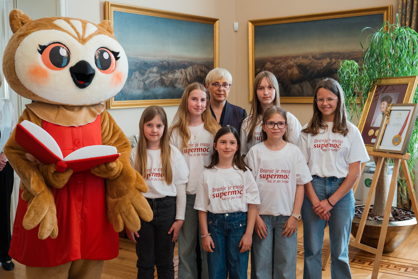 Predsednica s Sovico Karlo in osnovnošolkami, ki rade berejo.