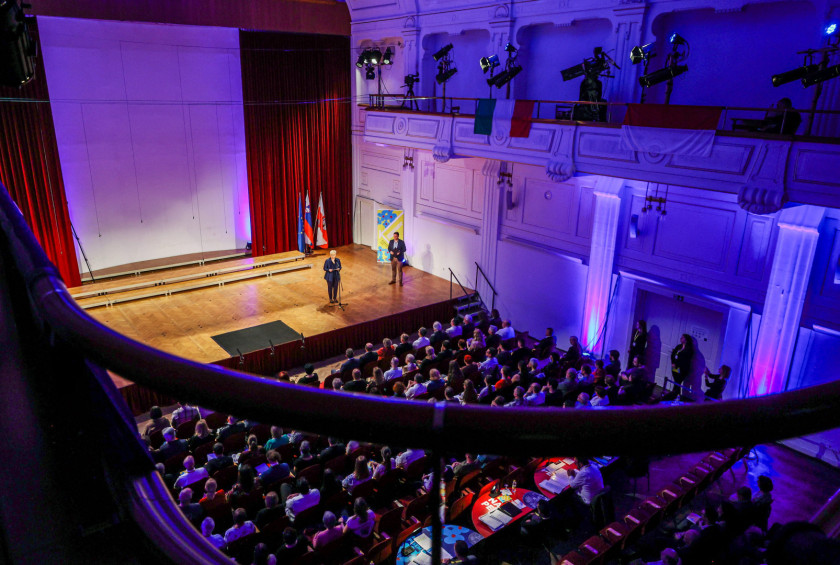 Predsednica ima govor na odru pred polno dvorano občinstva.