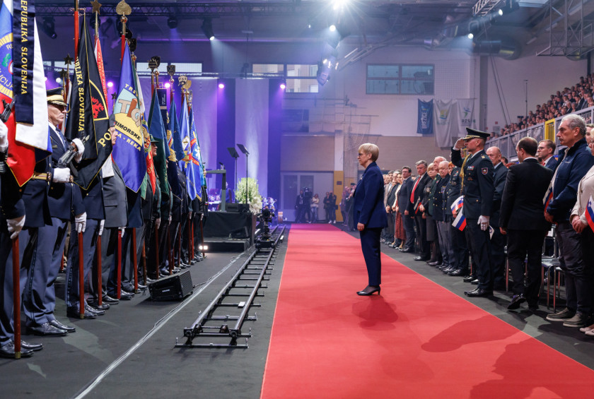 Predsednica stoji nekaj korakov pred prvo vrsto in se poklanja praporščakom.