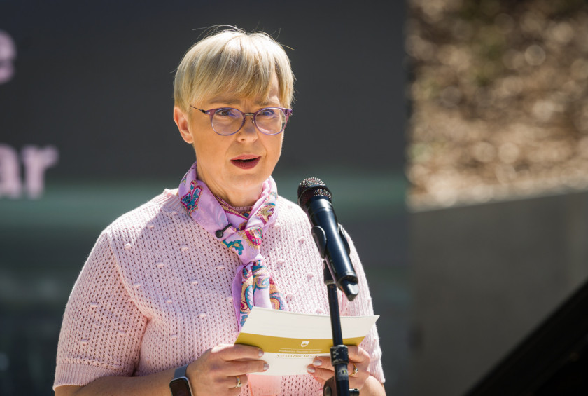 Bližnji posnetek predsednice, ki stoji za mikrofonom in nagovarja zbrane.