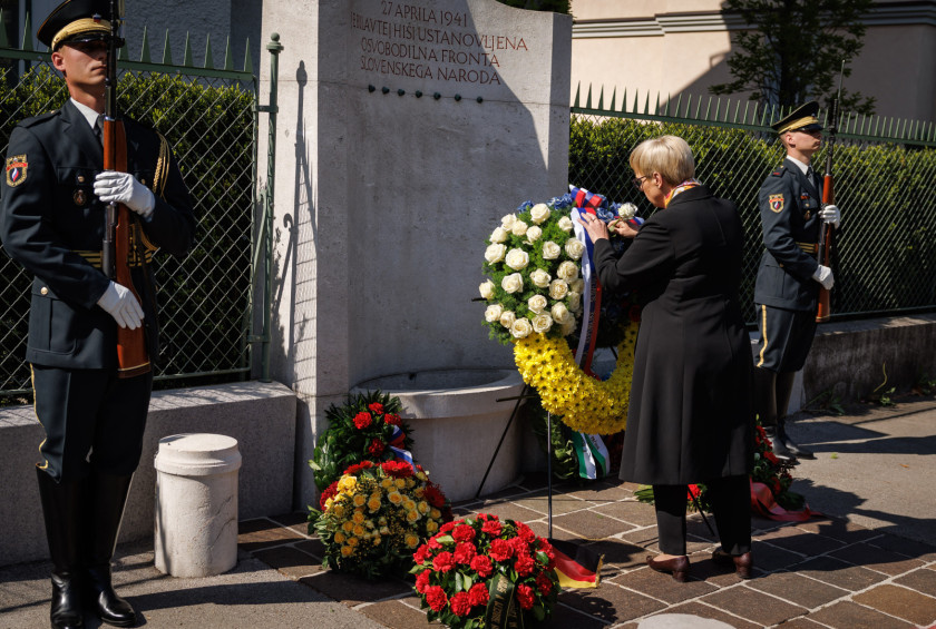 Predsednica popravlja trak na vencu pred spomenikom.
