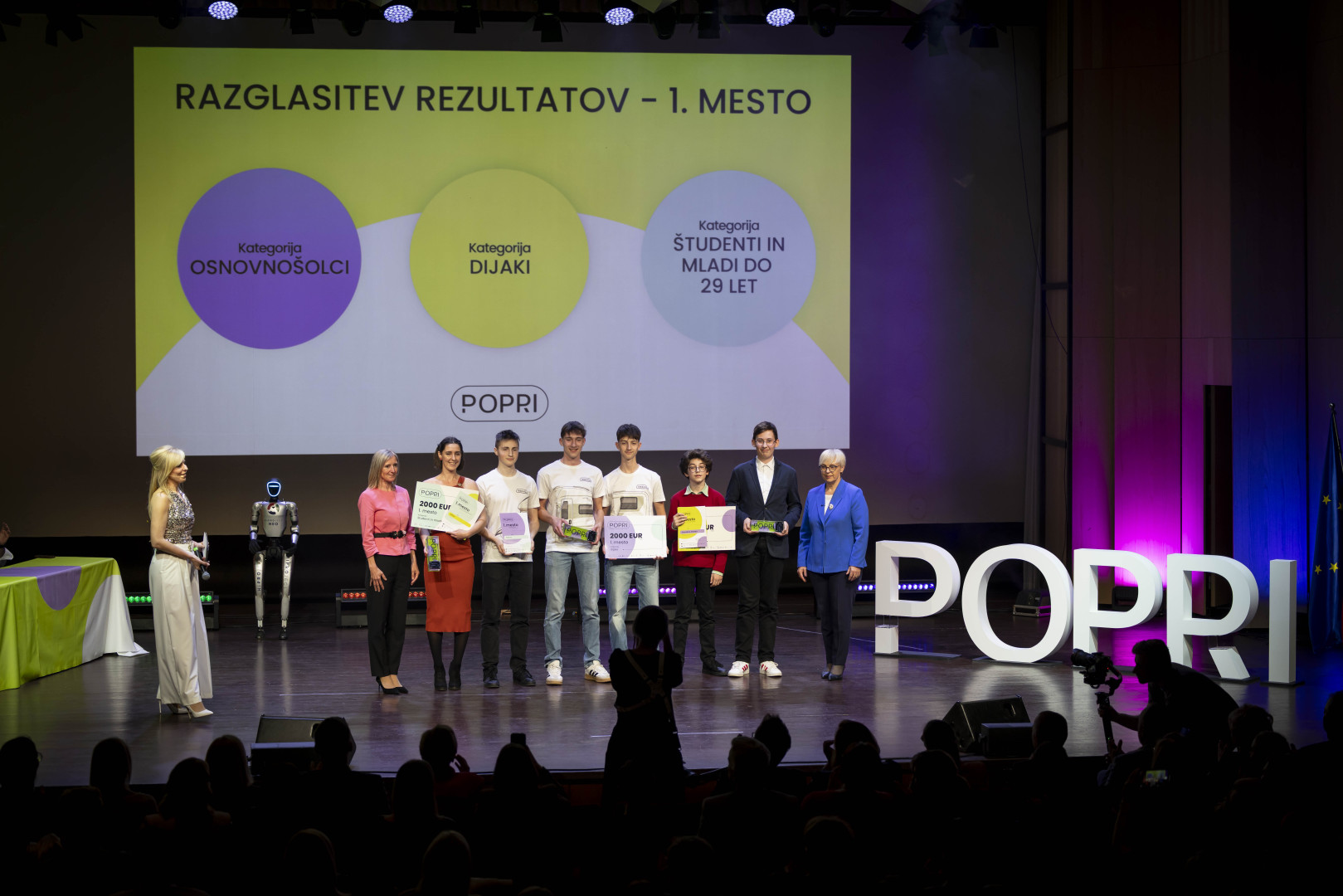Skupinska fotografija zmagovalcev natečaja POPRI na odru s predsednico.