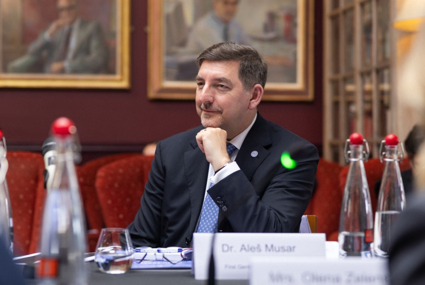 Fotografija soproga, ki sedi za mizo in spremlja predavanje.