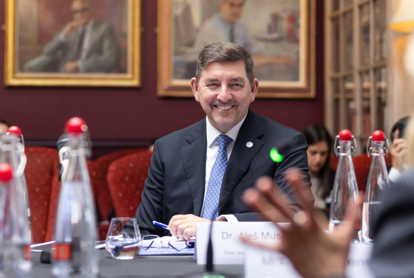 Fotografija nasmejanega soproga, ki sedi za mizo in spremlja predavanje.