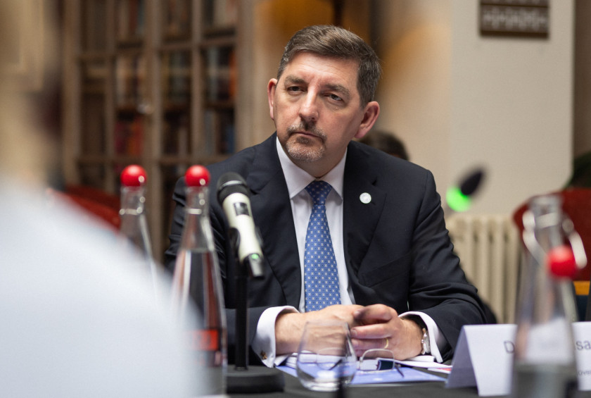 Fotografija soproga, ki sedi za mizo in spremlja predavanje.