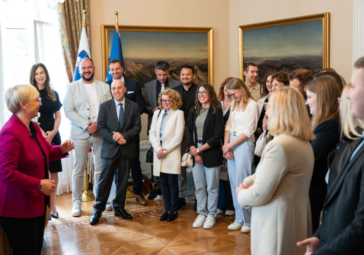 Predsednica v pisarni nagovarja nasmejane obiskovalce.