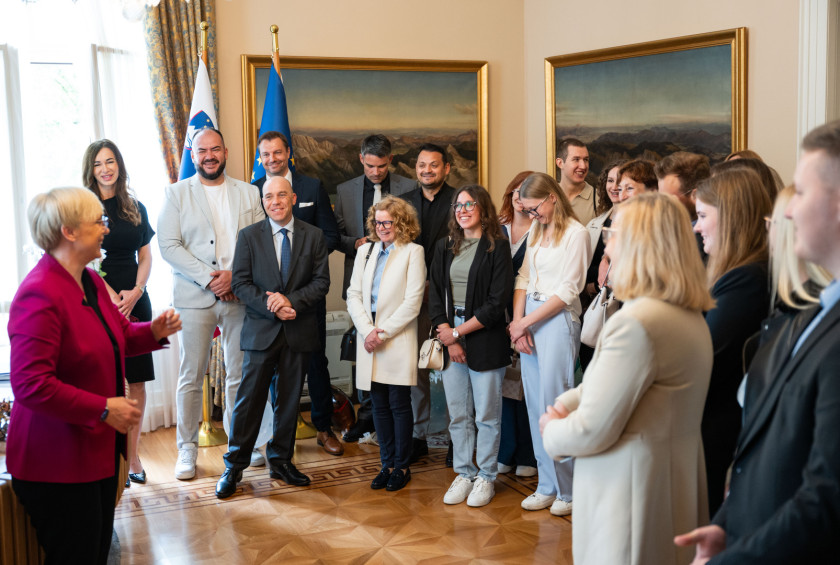 Predsednica v pisarni nagovarja nasmejane obiskovalce.