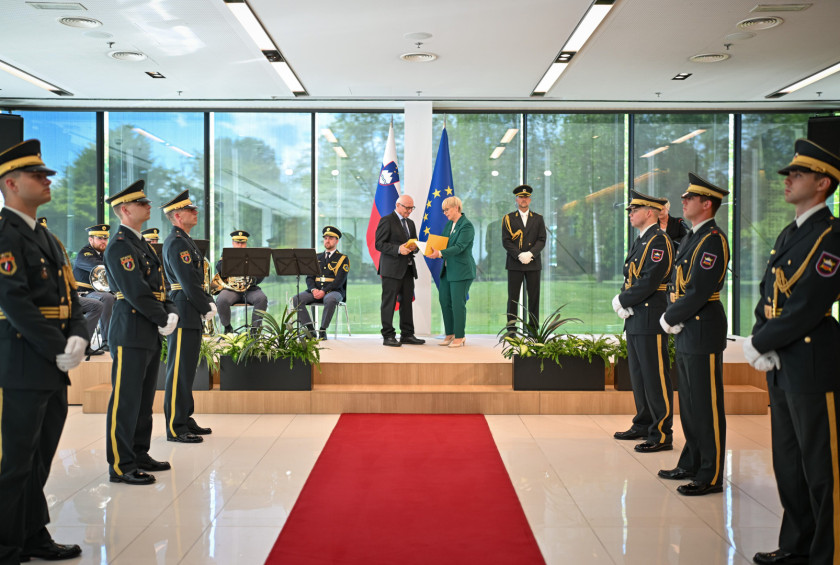 Predsednica republike vroča odlikovanje dr. Bratku, ob straneh stoji garda slovenske vojske.