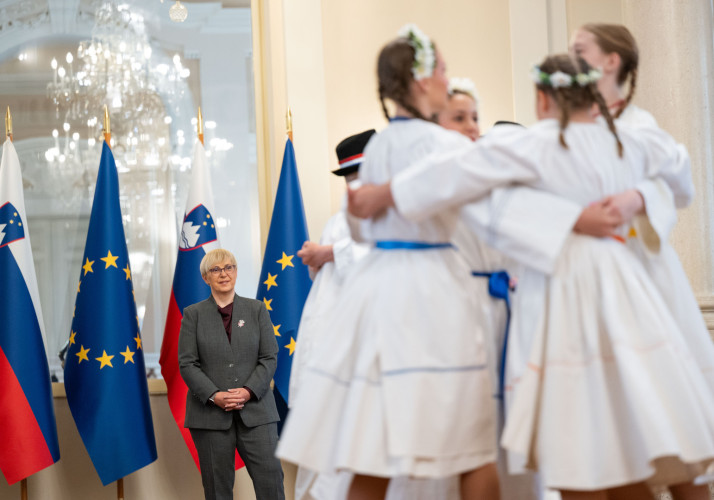 Predsednica opazuje deklice v narodnih nošah, ki plešejo.