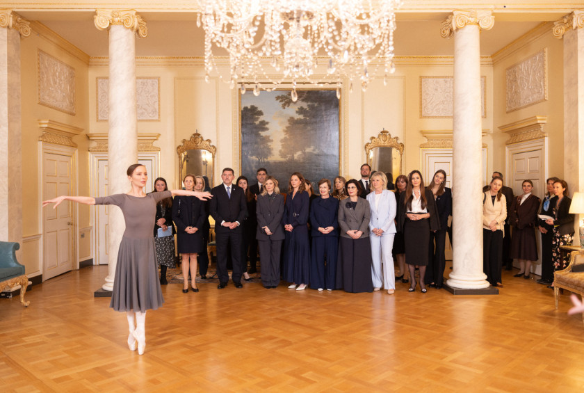 Skupina prvih soprog in soprogov ter udeležencev sprejema opazuje baletko, ki nastopa pred njimi.