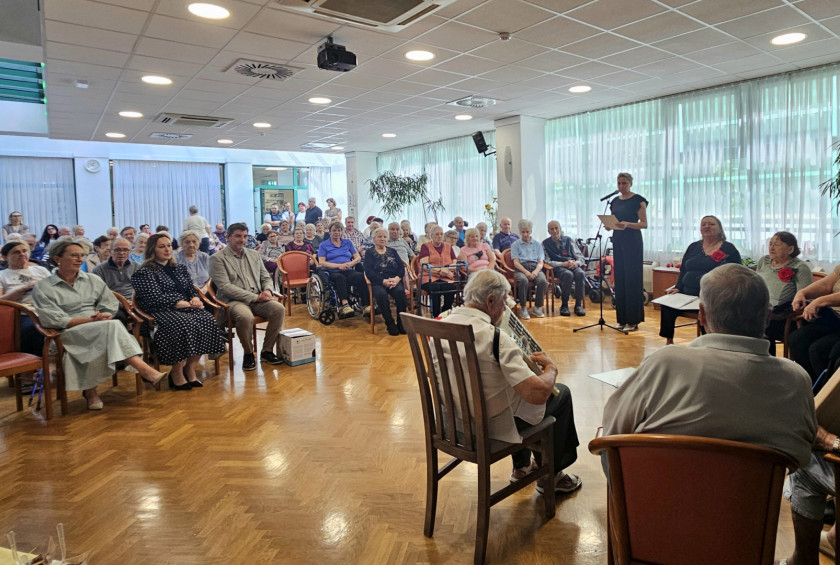 Stanovalci doma za starejše spremljajo kulturni program v skupnem prostoru.