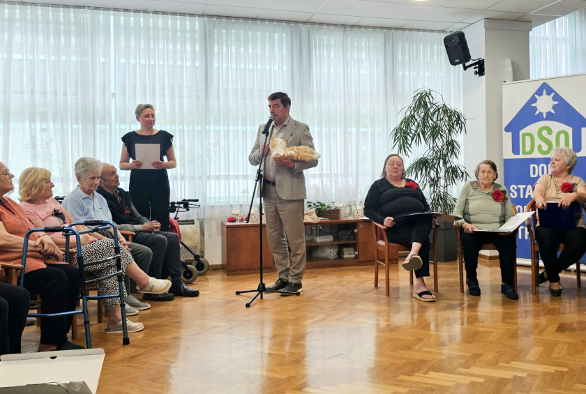 Dr. Musar med prireditvijo nagovarja zbrane in podarja plišasto mačko.