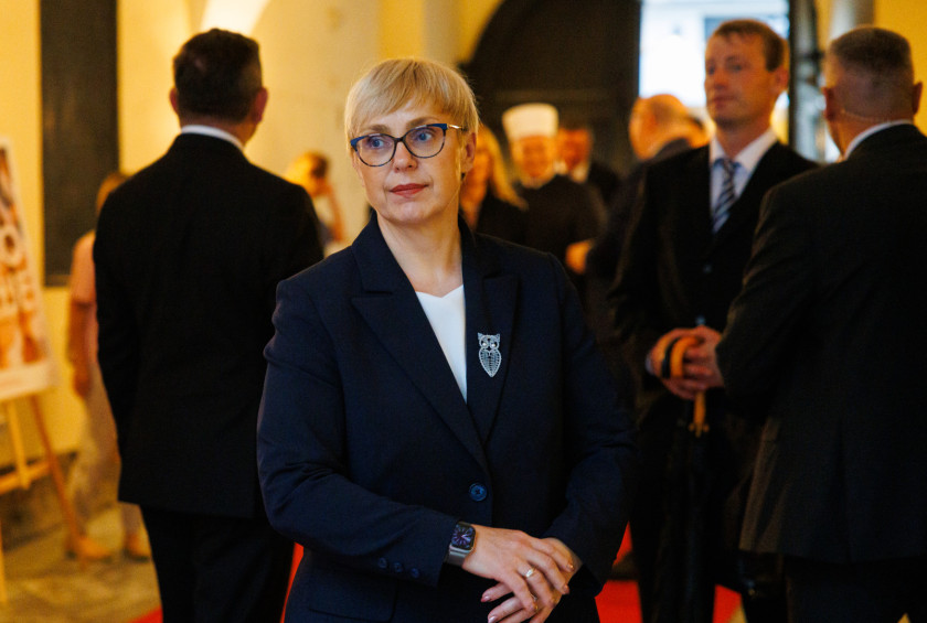 Predsednica stoji v preddverju in pričakuje druge udeležence sprejema.
