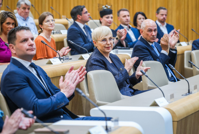 Predsednica sedi v dvorani Državnega sveta in ploska.