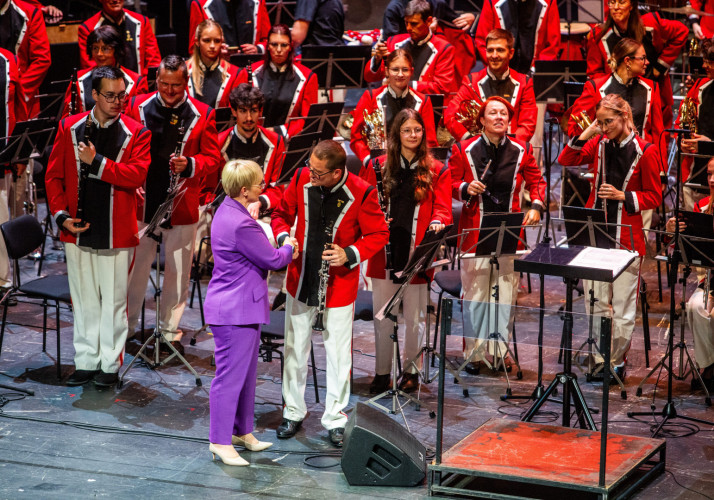 Predsednica se rokuje z glasbenikom Pihalnega orkestra Pošta Maribor na odru.