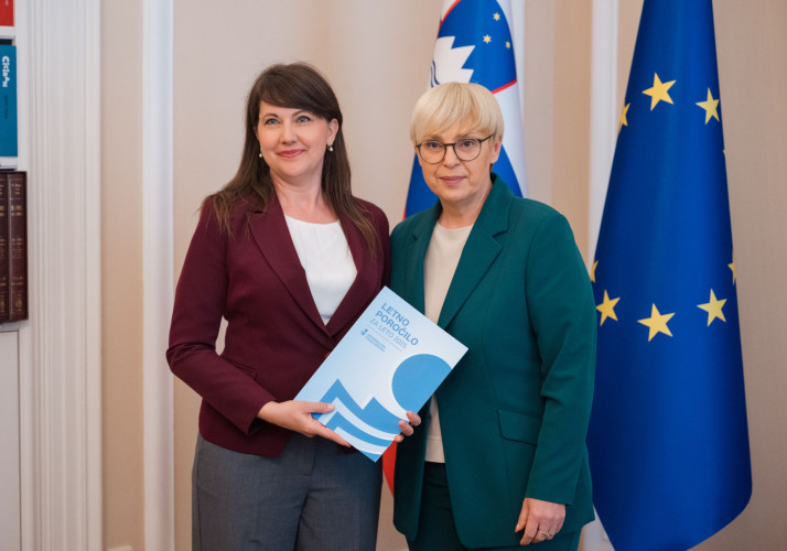 Informacijska pooblaščenka in predsednica stojita pred zastavami.
