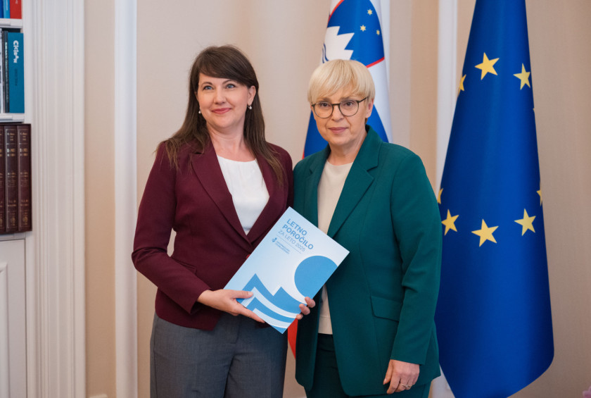 Informacijska pooblaščenka in predsednica stojita pred zastavami.