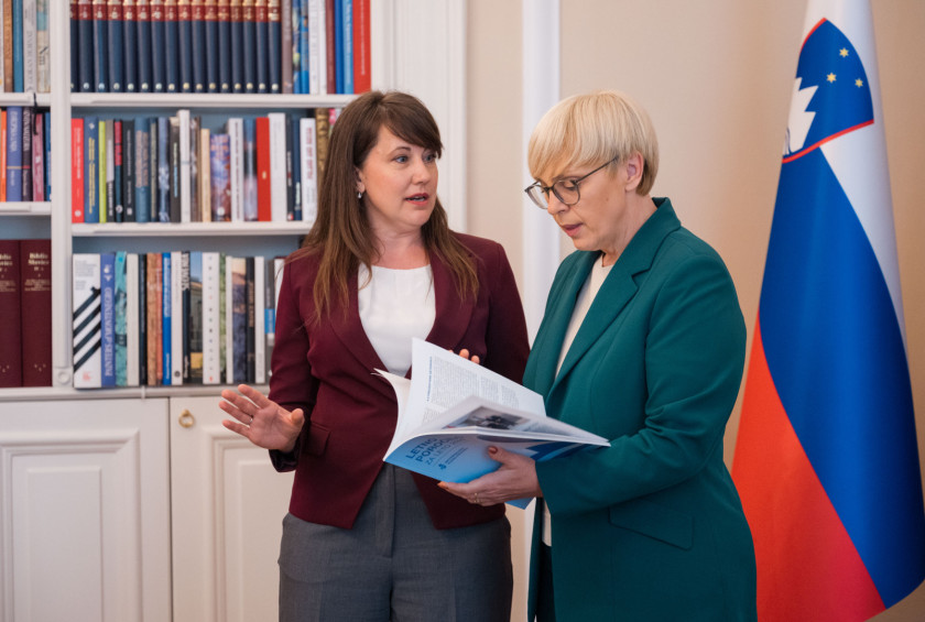 Informacijska pooblaščenka in predsednica stojita pred zastavami.