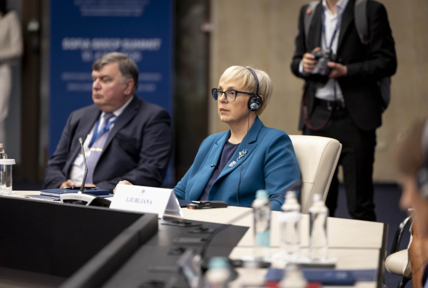 Predsednica sedi za omizjem s slušalkami in posluša.