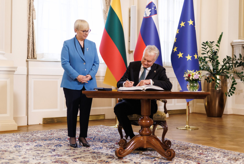 Litvanski predsednik se vpisuje v knjigo gostov, predsednica stoji ob njem.