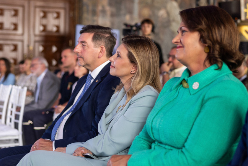 Soprog in drugi udeleženci dogodka spremljajo nastopajoče na okrogli mizi.