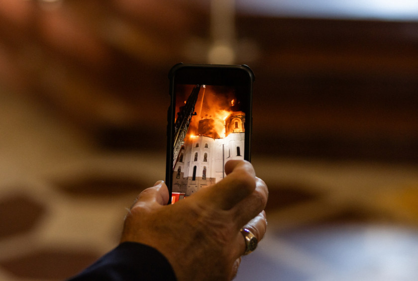 Fotografija prenosnega telefona, na katerem je videti goreč samostan.