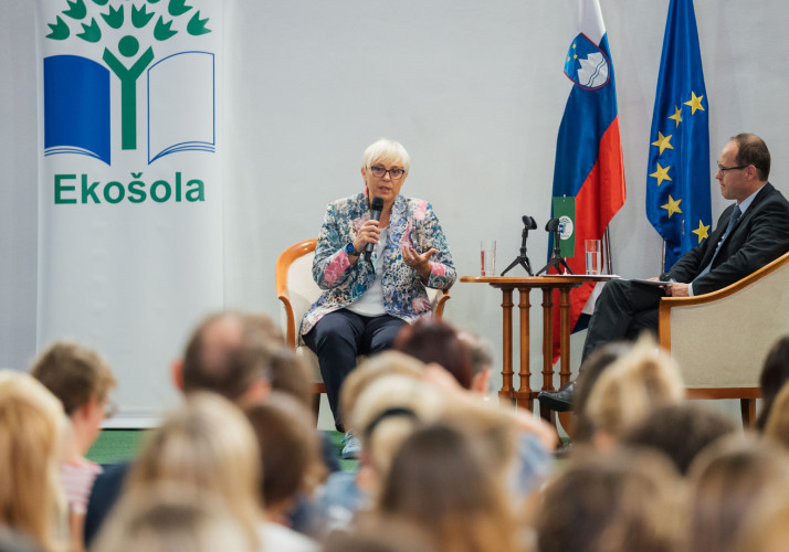 Predsednica sedi na odru in govori.