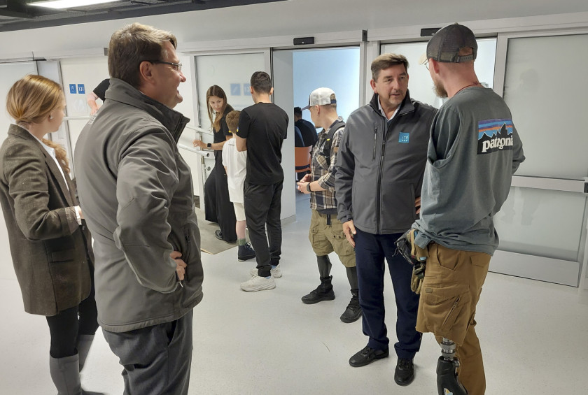 Dr. Aleš Musar se v rehabilitacijskem centru pogovarja z moškim s protezo noge.