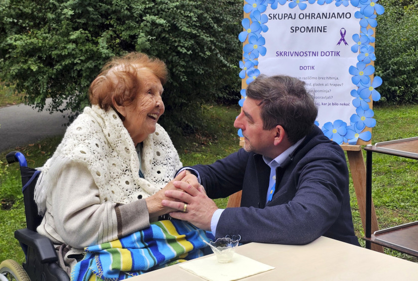 Dr. Aleš Musar se drži za roke z nasmejano oskrbovanko.