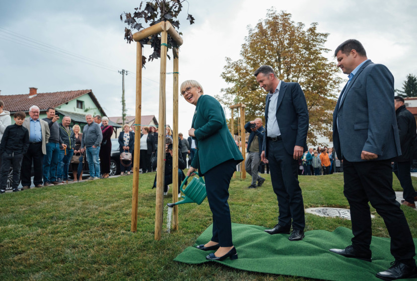Predsednica in župan zalivata drevo pred domom starejših.