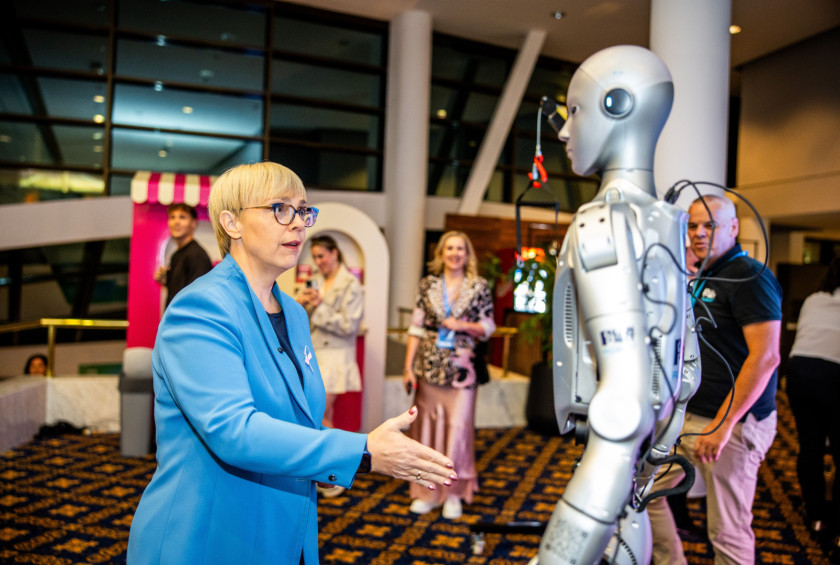 Predsednica republike ponudi roko robotu, ki pozdravlja goste. 