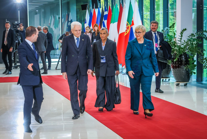 Predsednica z italijanskim predsednikom hodi po rdeči preprogi, v ozadju zastave.